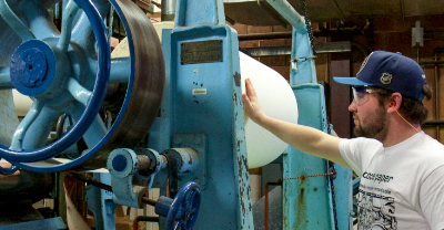 Student working with ESF's paper machine.