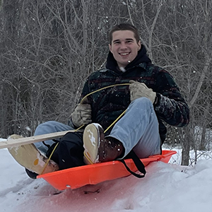 Man on a an orange sled at the top of a hill. 