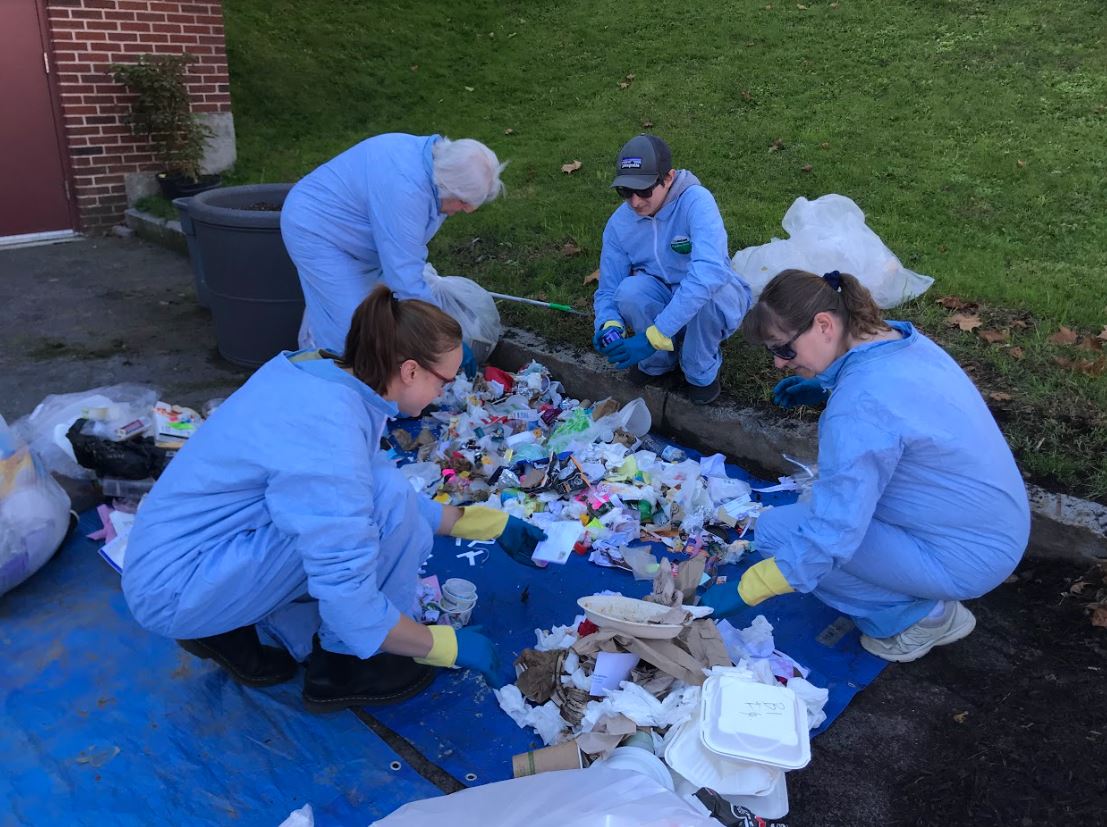 staff and students sift through trash during a waste audit