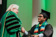 ESF President Joanie Mahoney shakes hands with a graduate.
