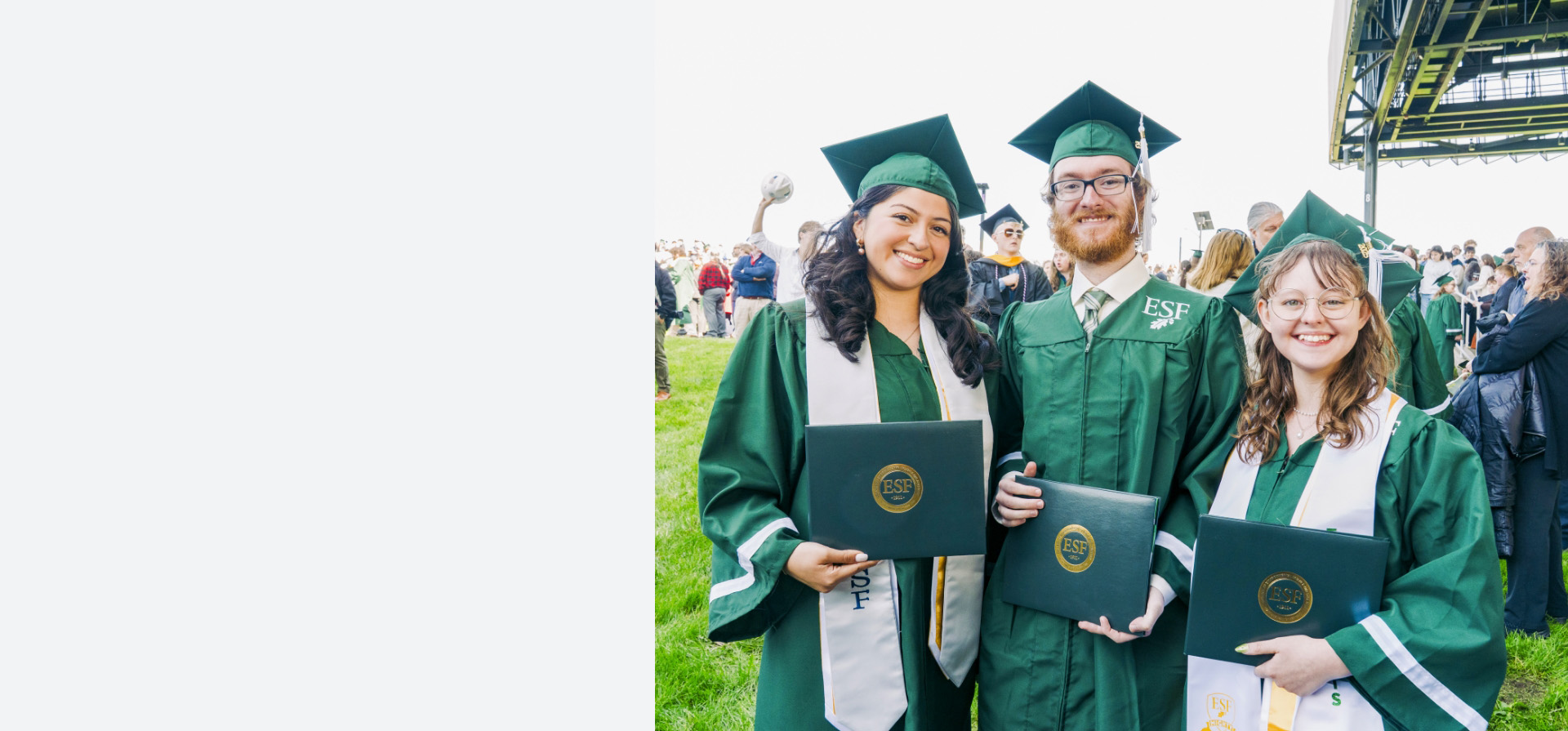 Three graduates pose with diploma covers at a past Commencement ceremony