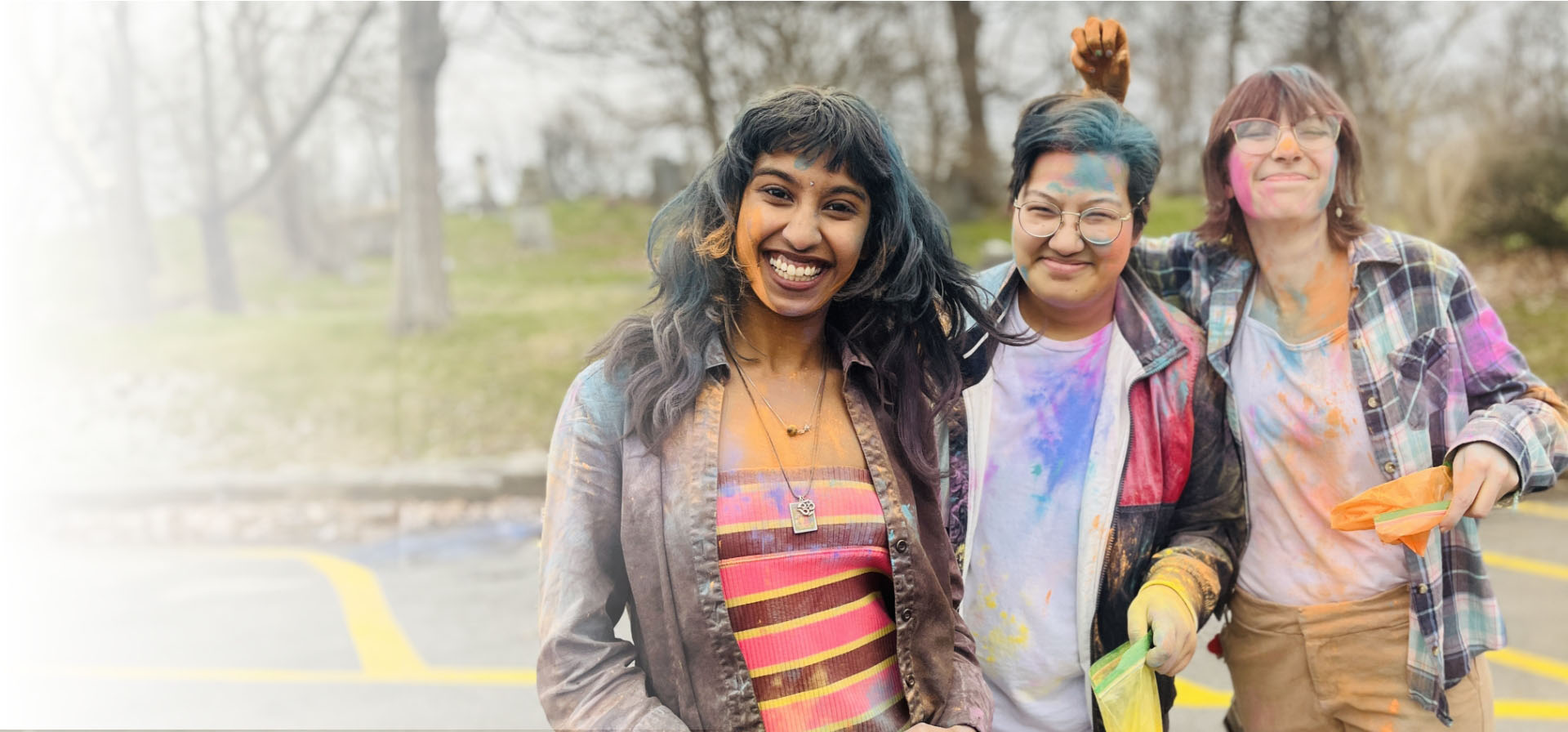 Three students standing in a parking lot holding dye powder.