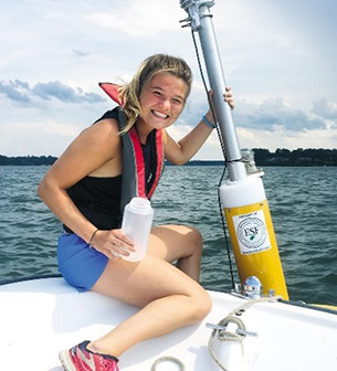 Recent graduate Kaela Natwora placing a probe in Lake Erie