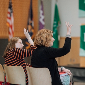 Two individuals raising hands in an orientation session.