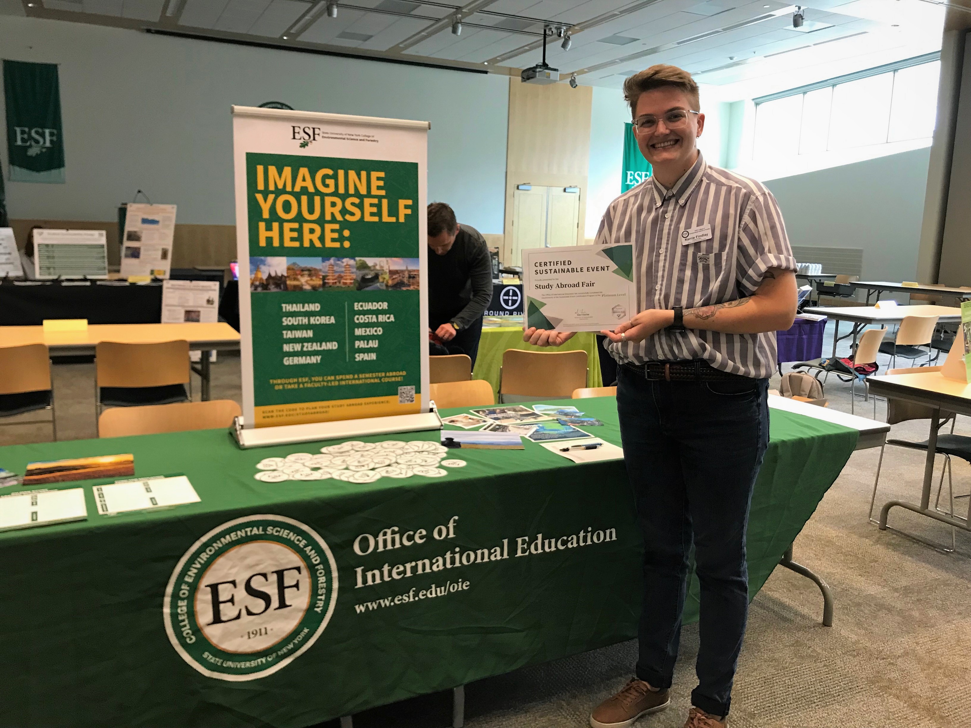 study abroad fair, staff member proudly holding sustainable event certificate