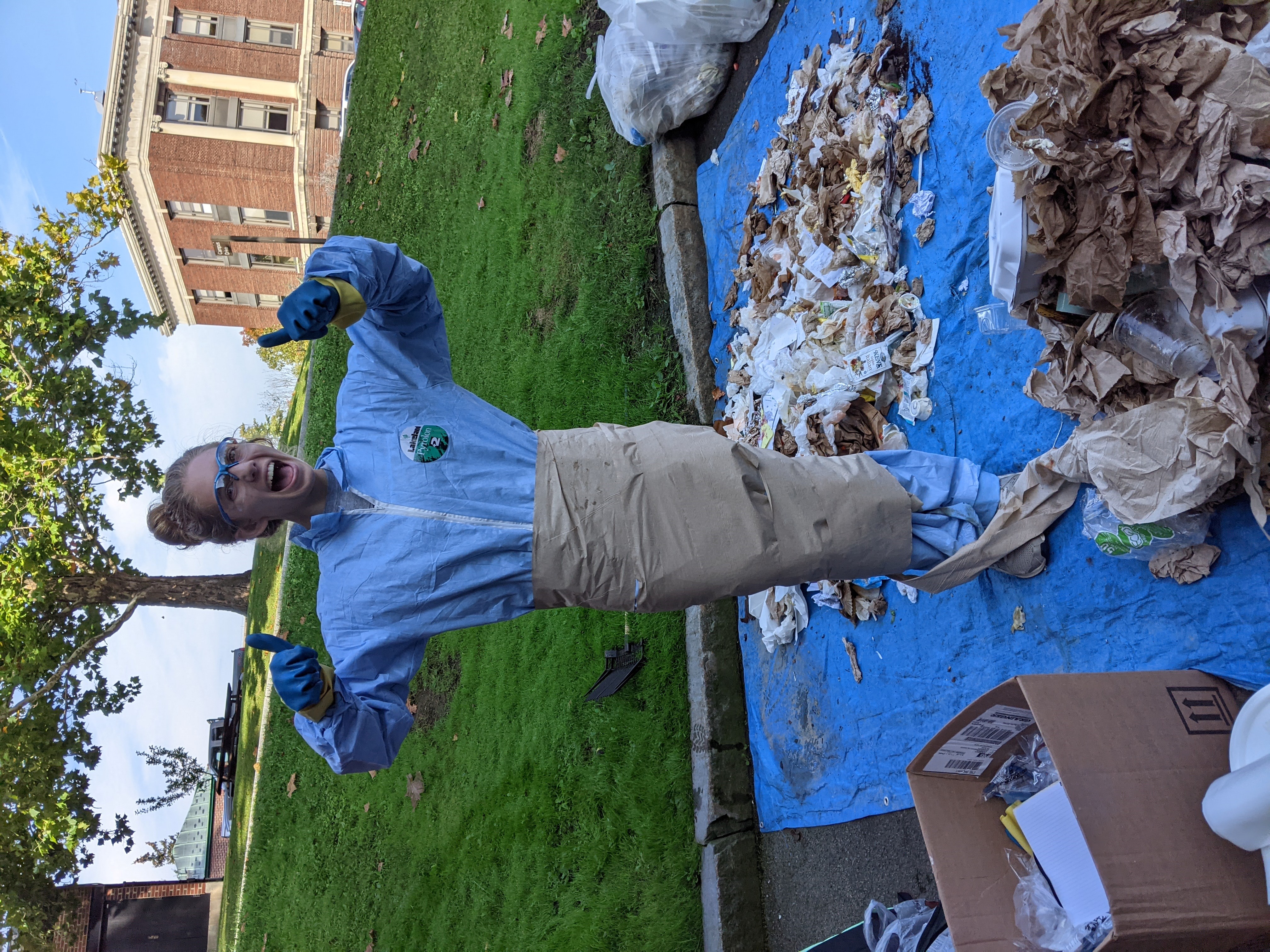 Club member wrapped in paper towels while conducting waste audit. Smiling, giving thumbs up