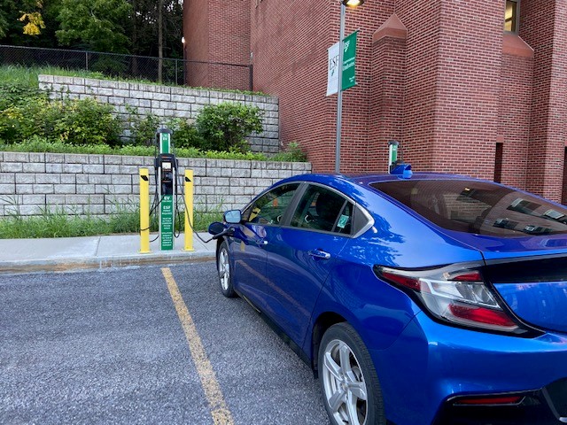 blue electric vehicle plugged in and charging on campus