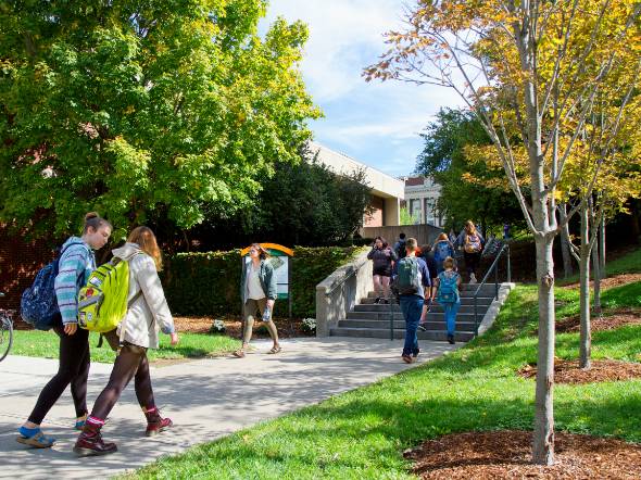 Students walking between Syracuse campus buildings in fall.