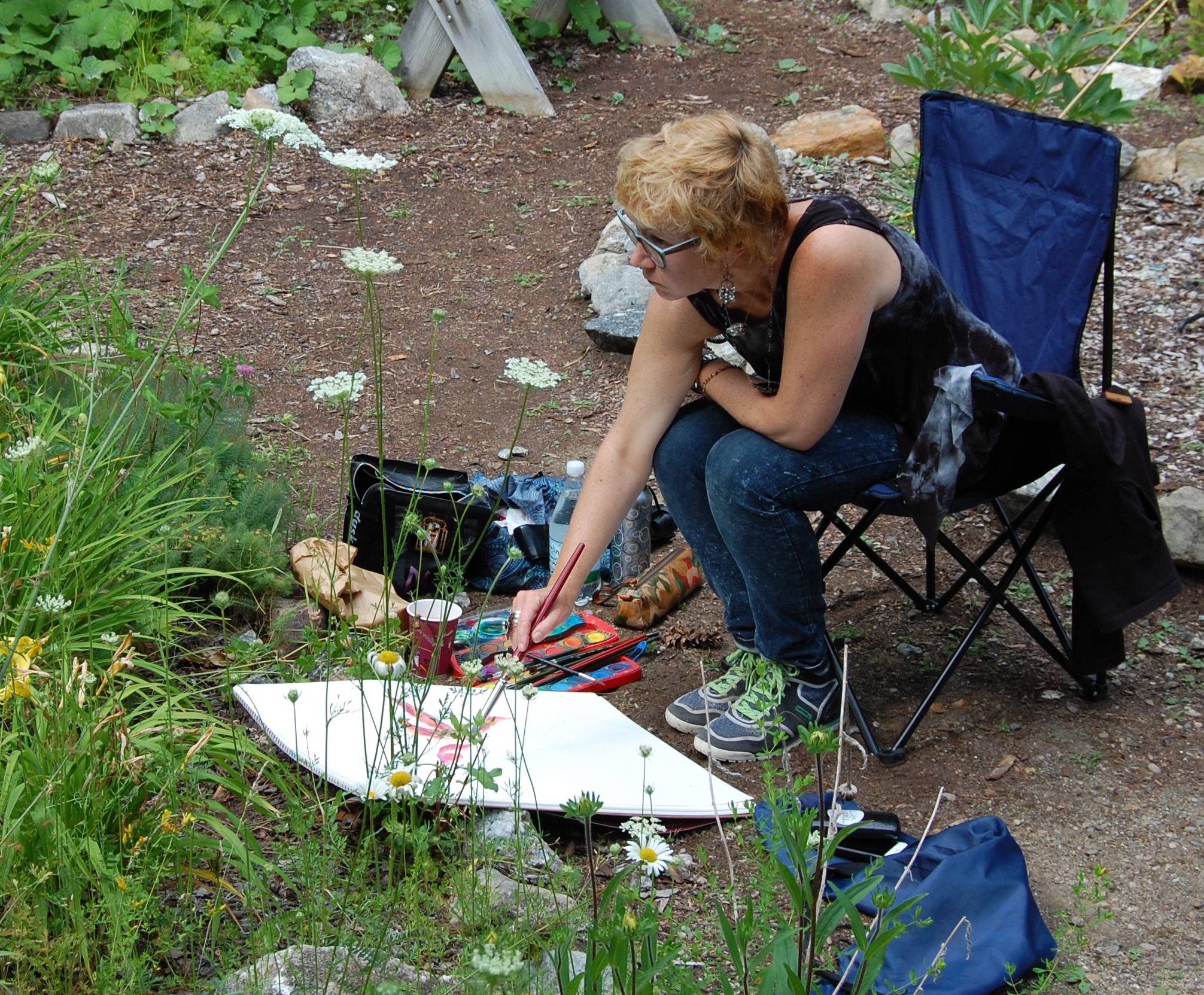 Marianna Trofimova siting in a chair and painting. She is outdoors