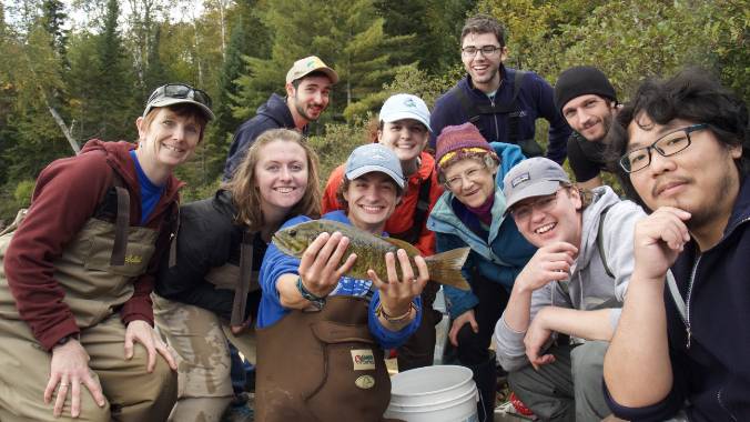 Students gathered surrounding one holding a fish.