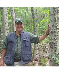 Peter Smallidge leaning against a tree