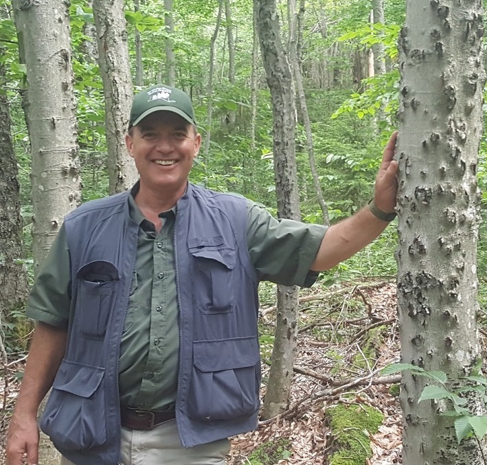 Peter Smallidge leaning against a tree
