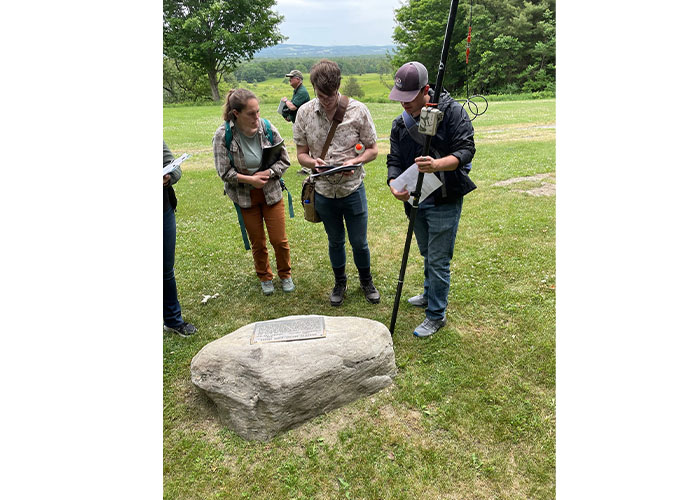 students looking at a plaque on a rock