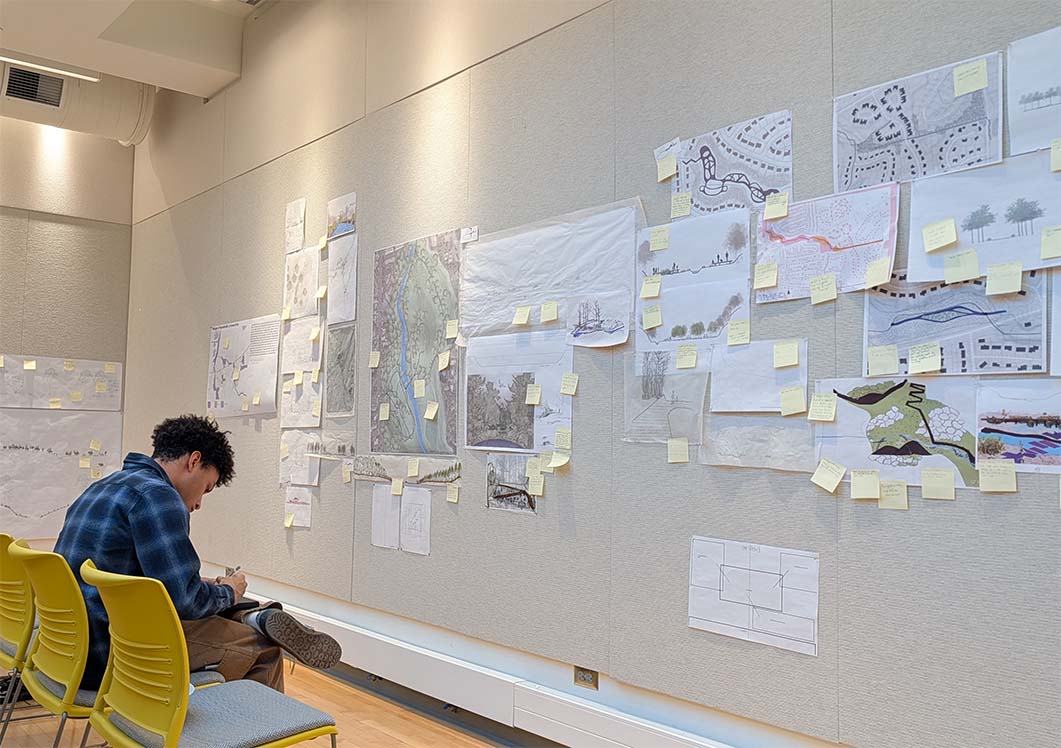 A student taking notes. The wall in front of the student is full of post-it notes