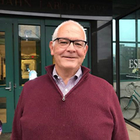 Richard List smiling in front of Jahn Laboratory building at ESF. He is wearing a Shirt and maroon pullover.