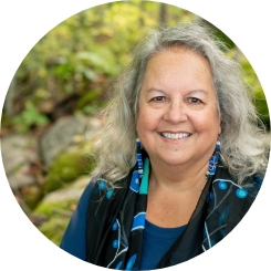Photo of older native female Robin Kimmerer is nice blouse framed by outdoor greenery