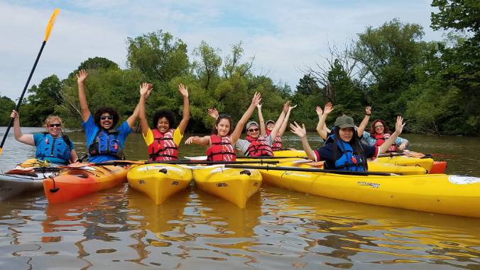 Students in canoes with hands raised