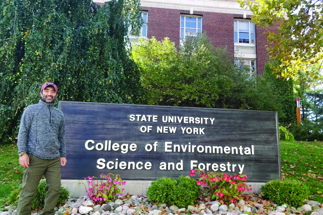 Abishek Poudel standing next to the State University of New York College of Environmental Science and Forestry sign