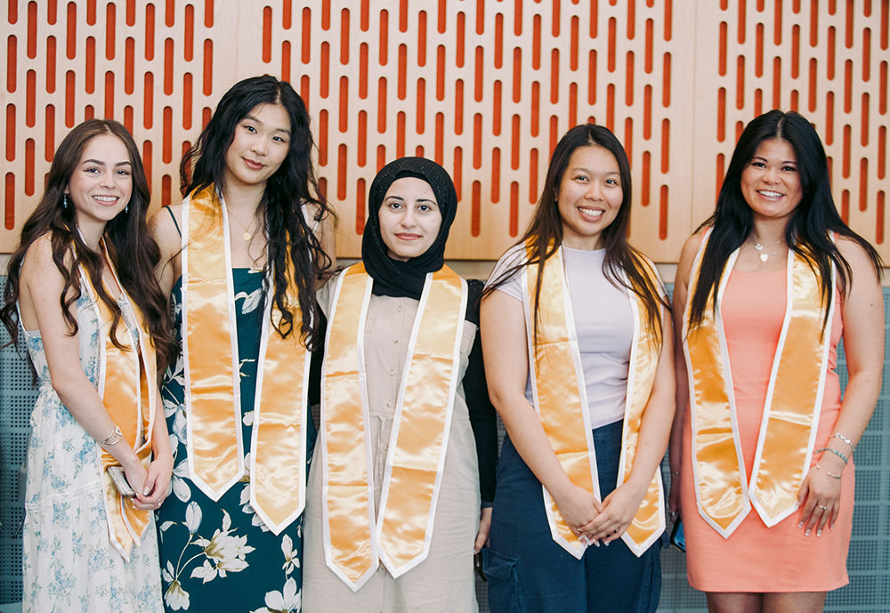 Five female students wearing dresses and gold sashes