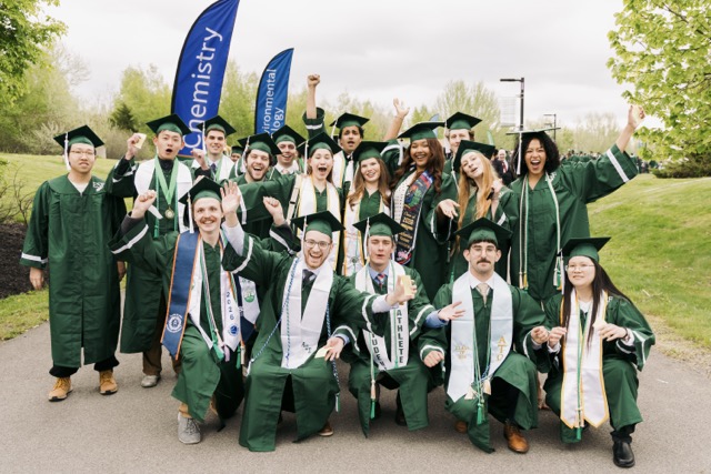 Group of students posing for the camera in their graduation regalia looking happy