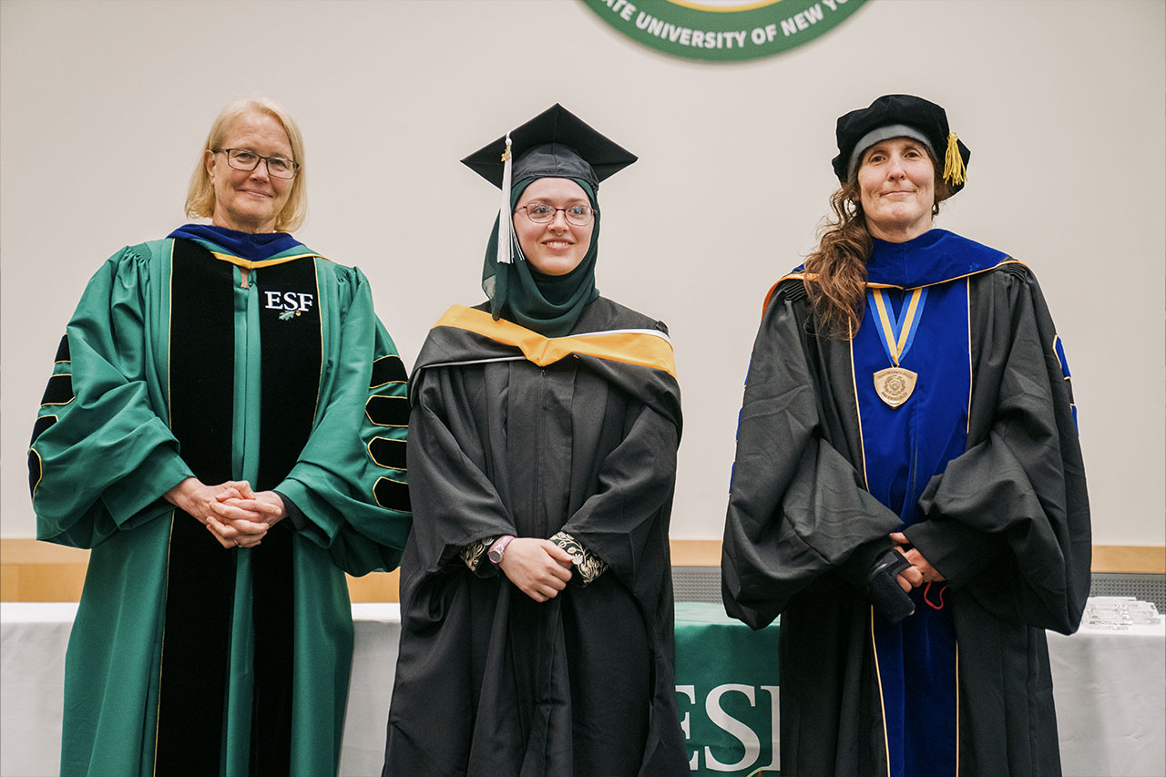 The women in higher degree regalia posing for the camera