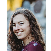 headshot of nicole schuster. She is wearing a purple top and smiling