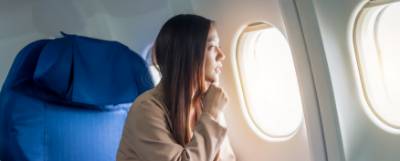 Woman seated on a plane looking out a window.