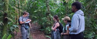 Students standing along a path in woods.
