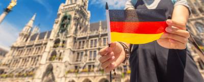 Person standing outside a building holding a German flag.