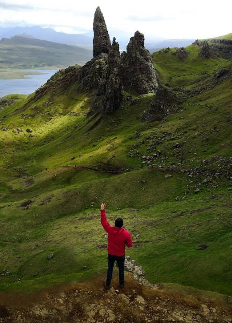 Student standing in front of a mountain in Scotland with a waterway in the distance.