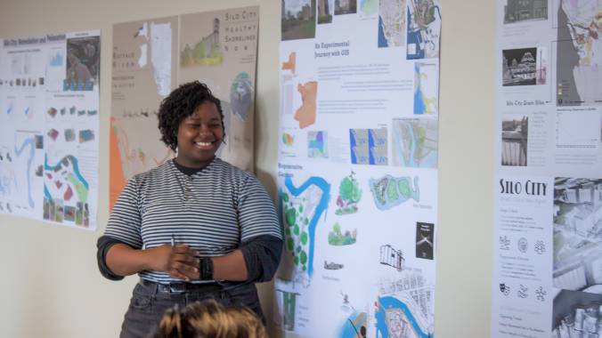 Student presenting a poster along a wall.