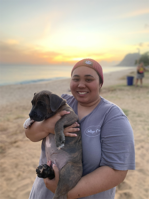 Navares holding a puppy on a beach. 