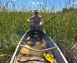 Madeline Nyblade in a row boat surrounded by tall grass