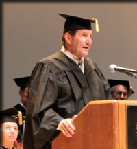 Roger Sedjo in graduation cap and gown standing on a podium