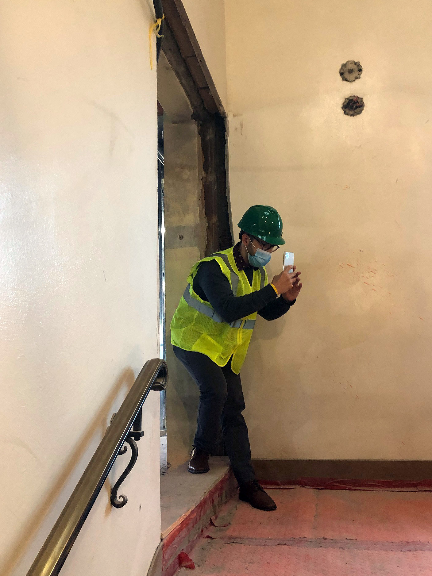 David Hass in marshall hall wearing a safety vest and hat taking a picture using his phone