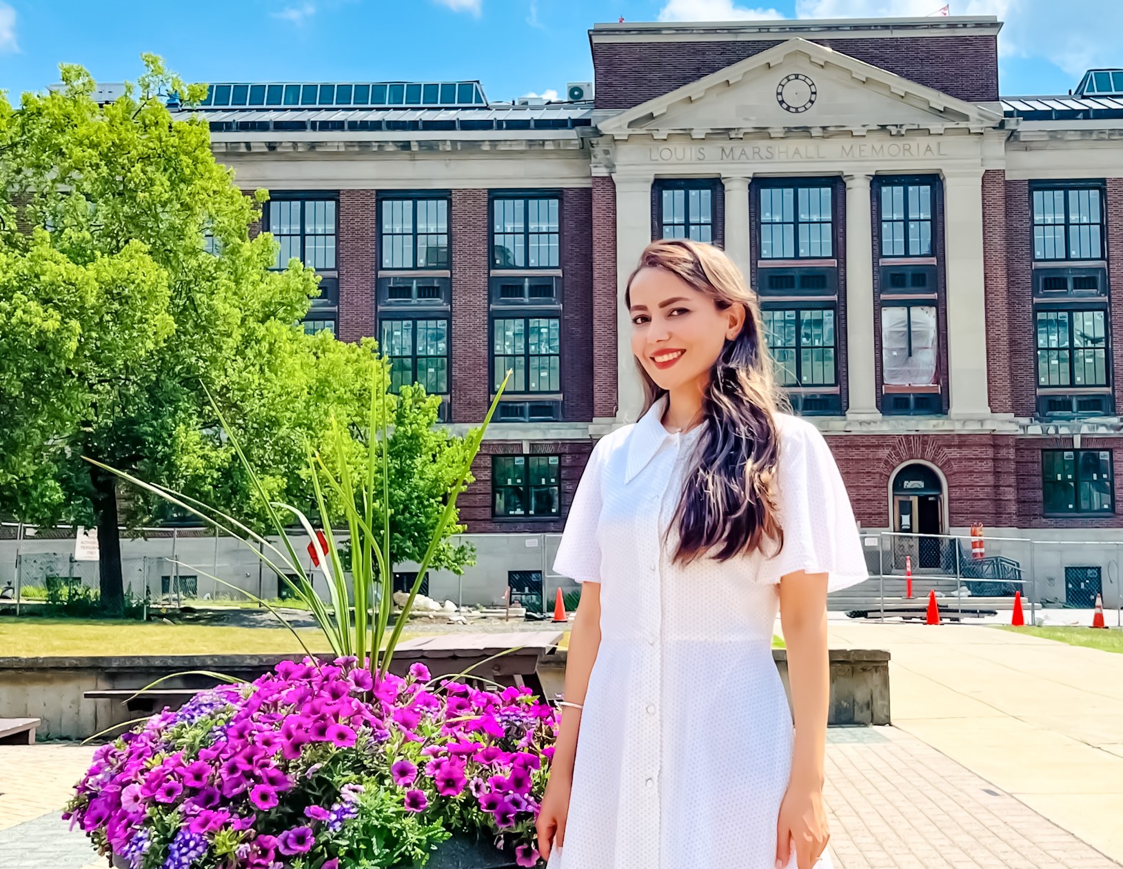 Maryam in a white dress standing in front of Marshall Hall at ESF