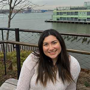 Woman with a white sweater on sitting with lots of nature in the background. 