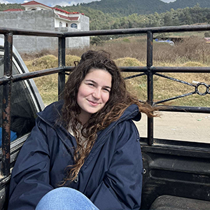 Woman in a jacket sitting out in nature. 