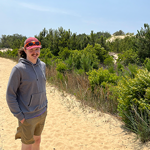 Man in a red hat standing with nature around. 