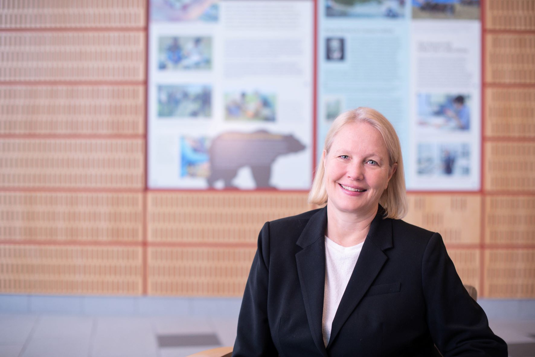 Woman standing in a room with brown paneling and an info panel that has a brown bear on it. 