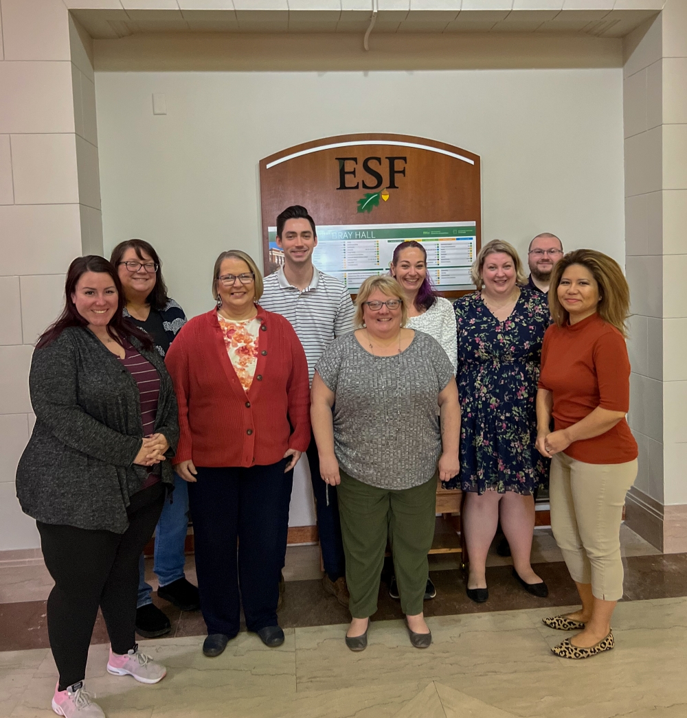 Group of people standing in front of an ESF wooden sign.
