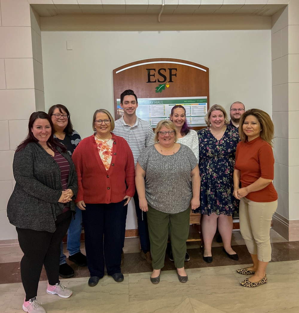 Group of people standing in front of an ESF wooden sign. 