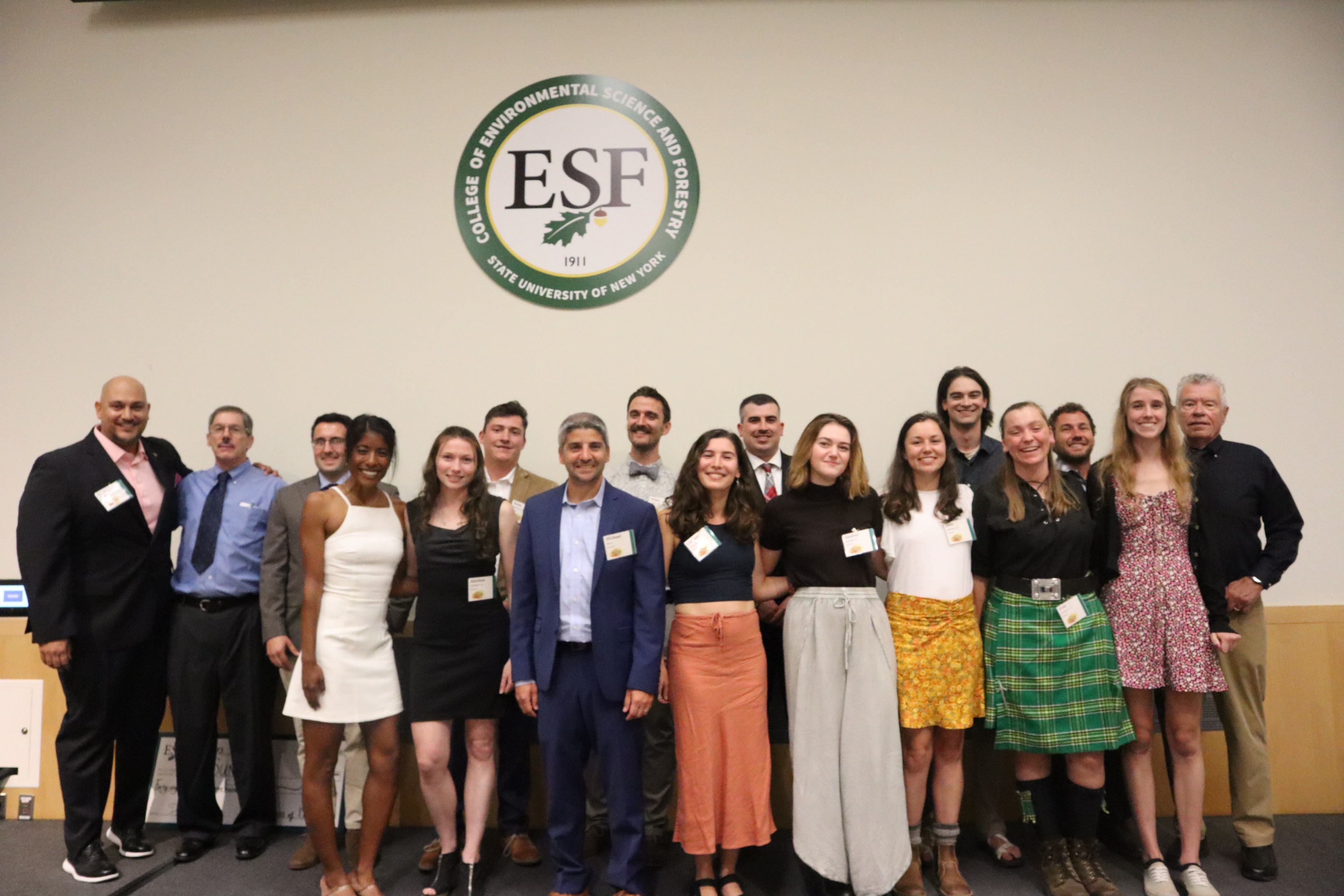 Eighteen people standing together for a group picture in front of ESF logo.