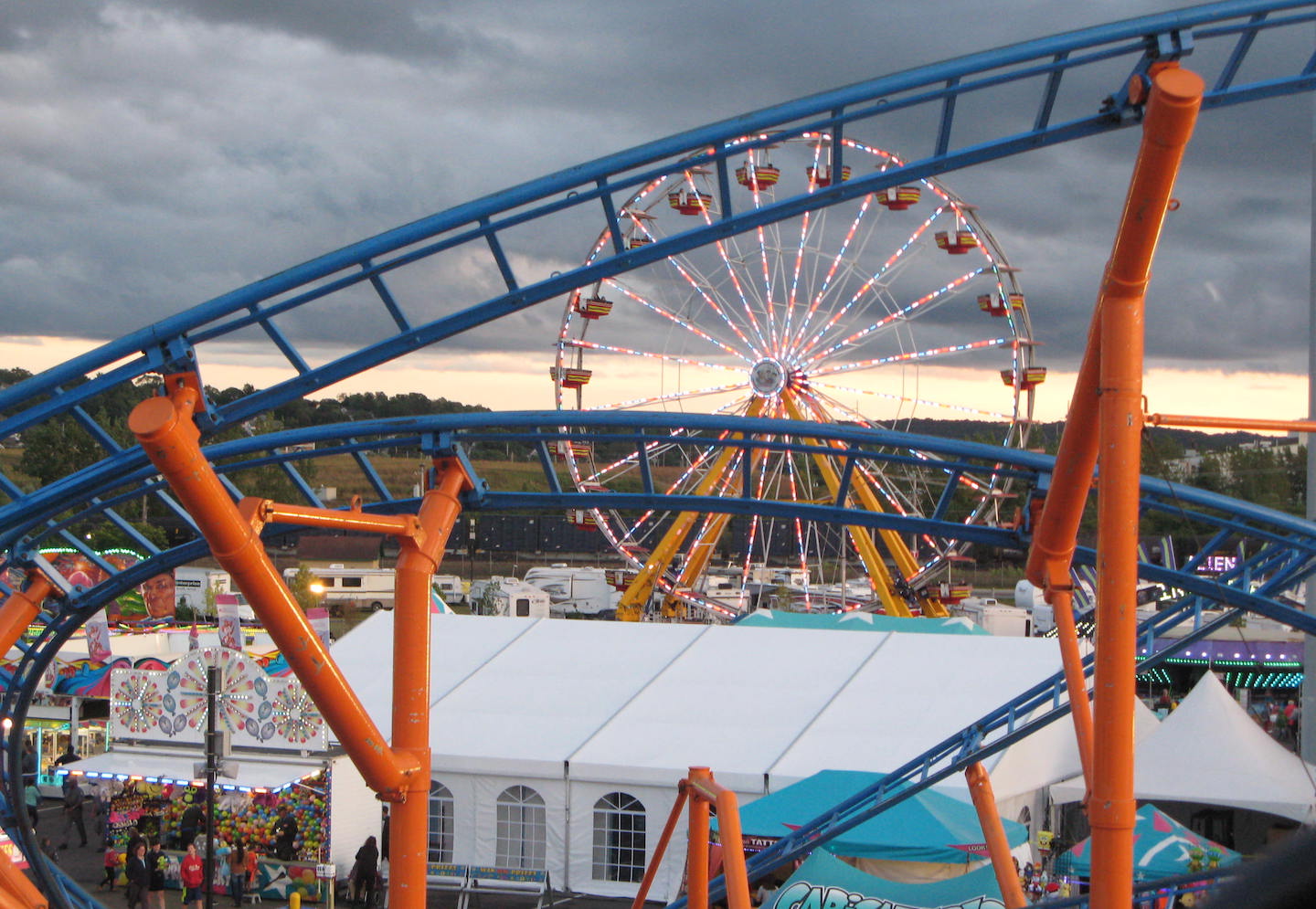 Picture of ferris wheel seen through roller coaster tracks.