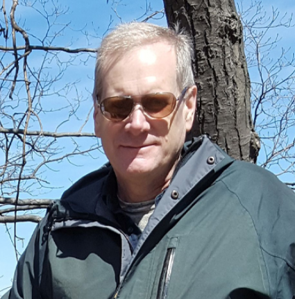 Man wearing blue jacket and sunglasses standing outside