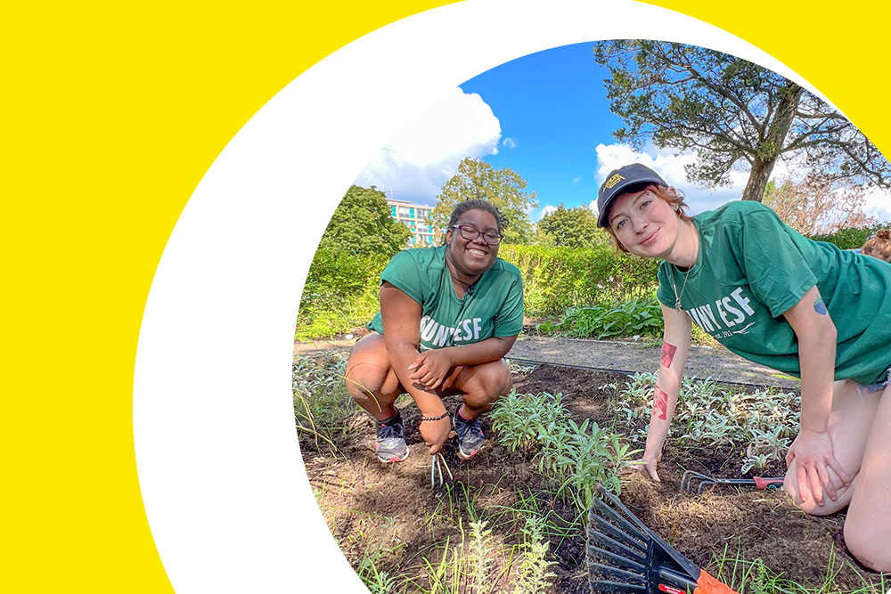 two SUNY ESF First Year female students posing for the camera while gardening at the annual saturday of service event