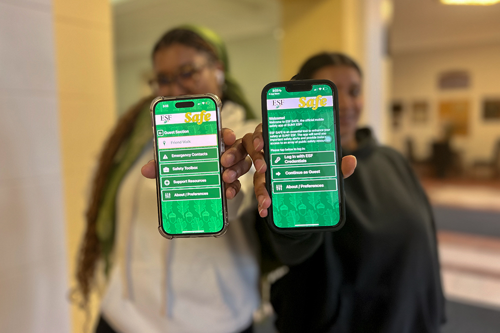 Close-up of phones with safety app open held by two people blurred in background