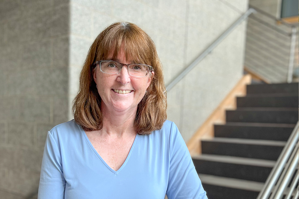 Woman wearing light blue sweater and glasses.