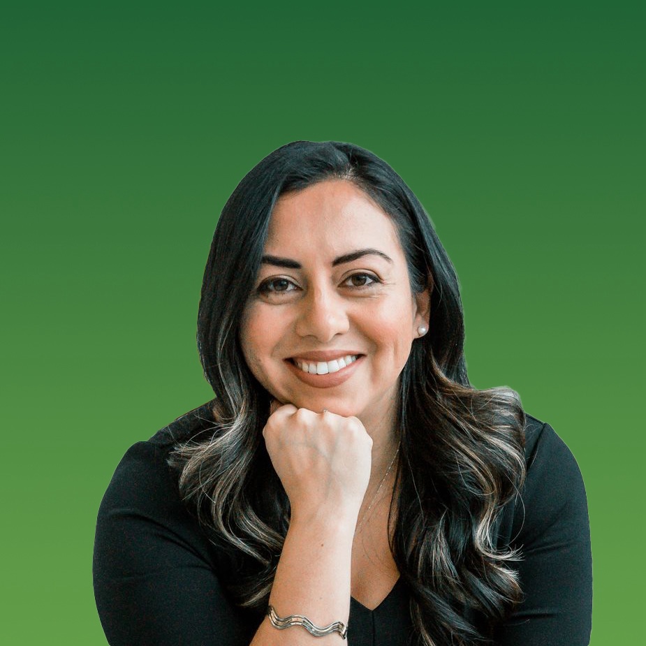 Smiling woman with long dark hair resting her chin on her fist in front of a green background.