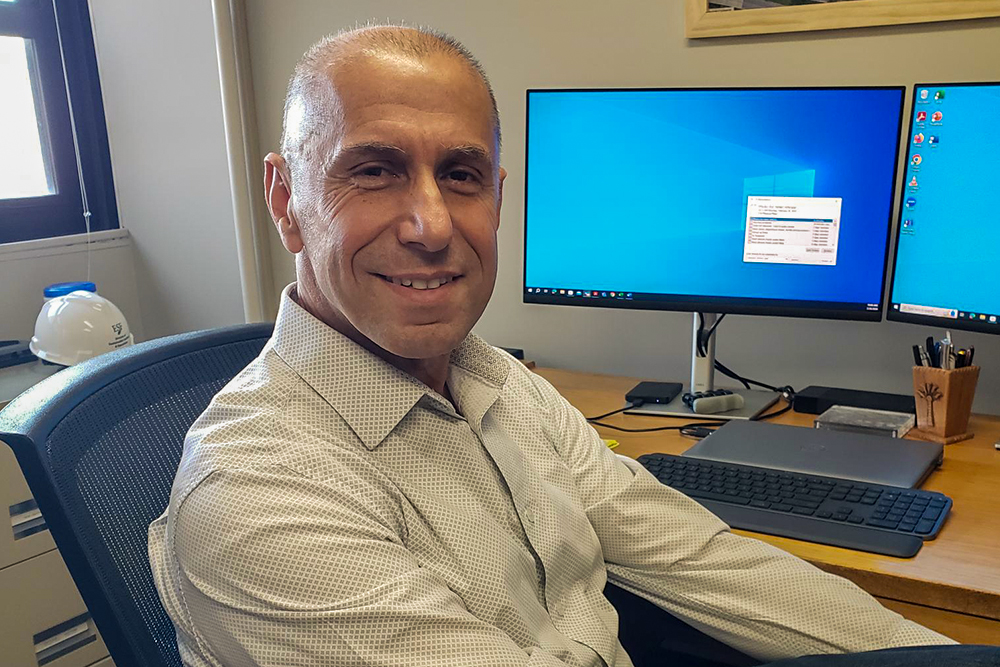 Man in beige dress shirt sitting in front of computer.